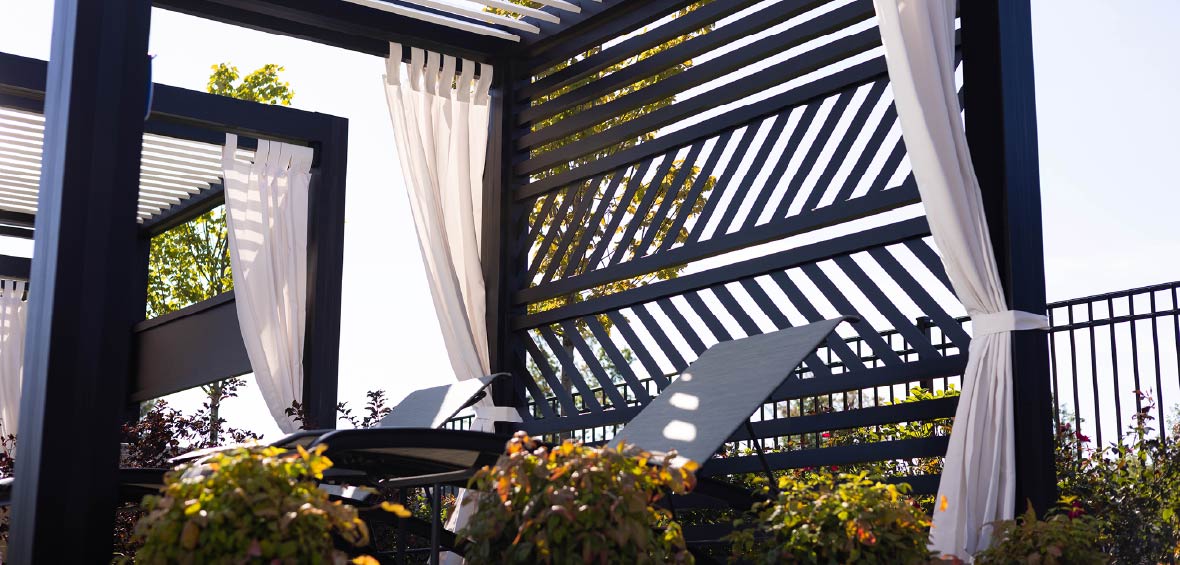 A cabana with curtains tied to the side provides shade for a small sitting area. 
