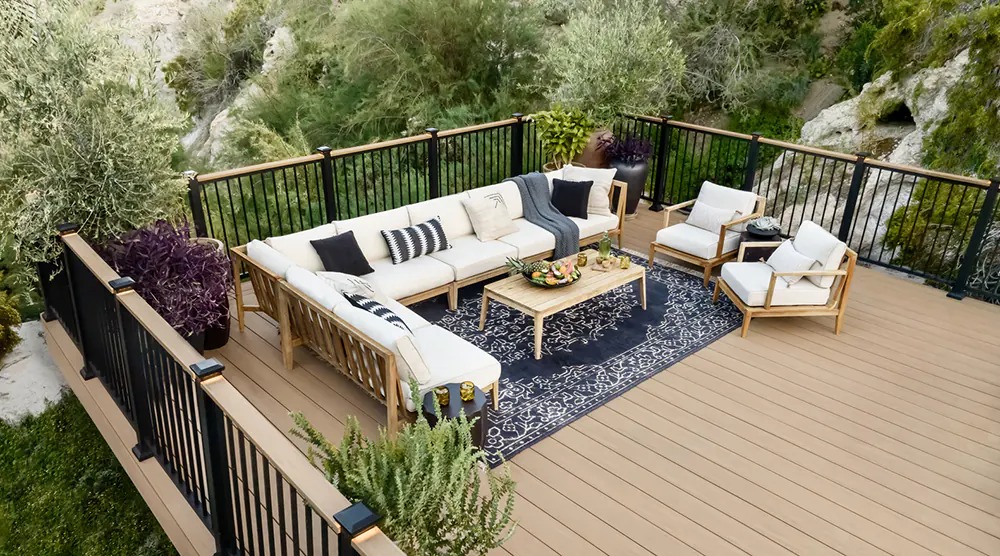 Woven outdoor furniture on a tan deck with a wide staircase leading up to it