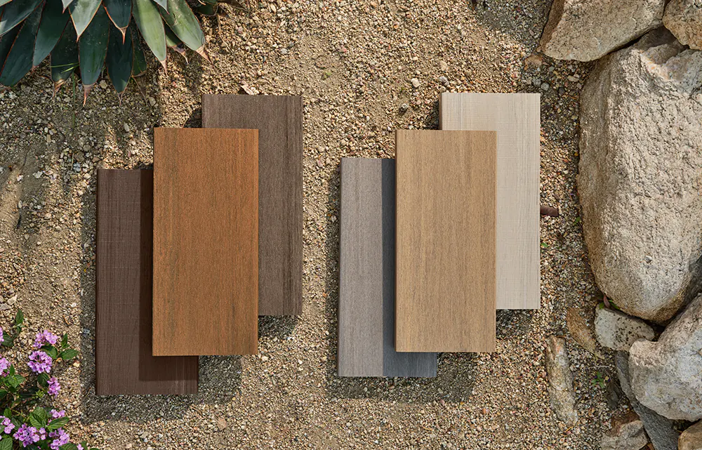 Six decking samples in different colors and board textures from TimberTech lay atop each other in the desert.