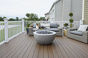 Australian Shepard dog lounges on an outdoor couch on a dark brown deck