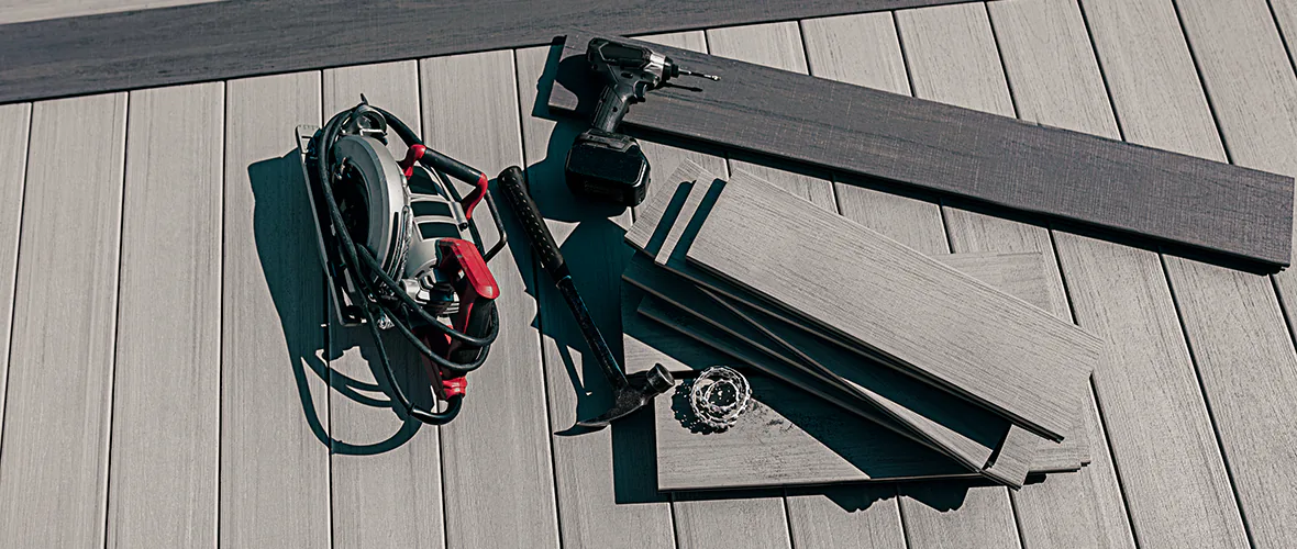 Several tools needed to build a deck are shown including a drill, hammer, and circular saw.