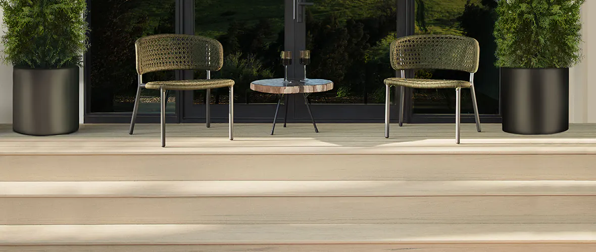 Chairs atop an elevated deck with two wine glasses on a coffee table between chairs. Cheers to designing a unique deck that matches your home.