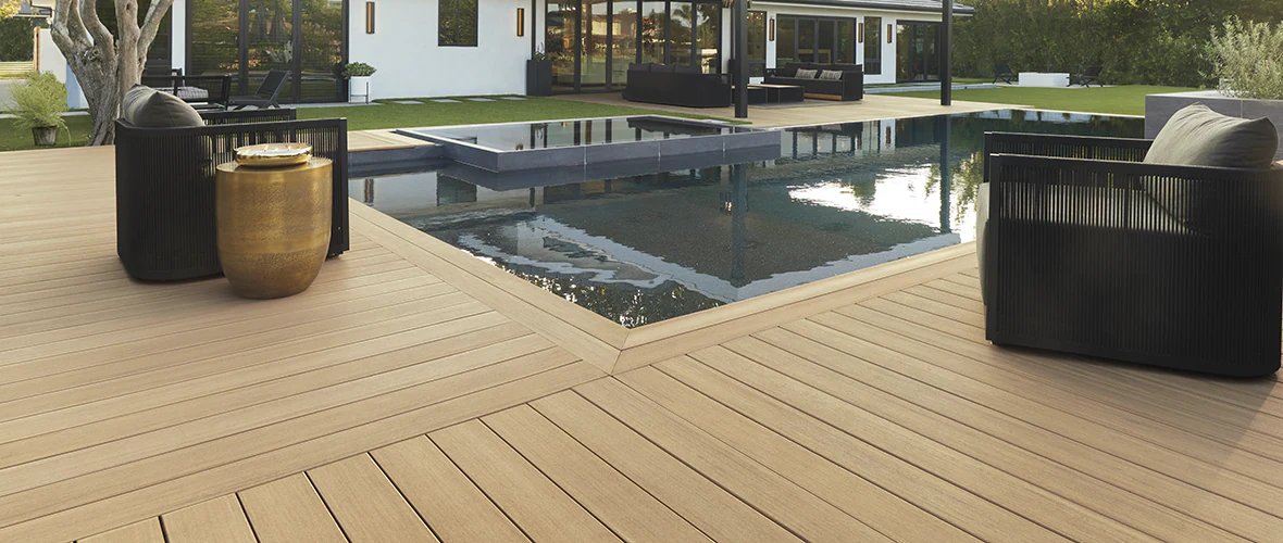 An expansive tan deck surrounds an in-ground pool in the backyard of a home