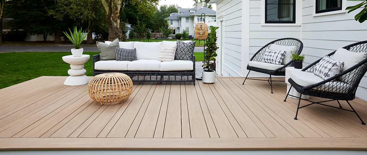 A deck with a white couch and a white chair.