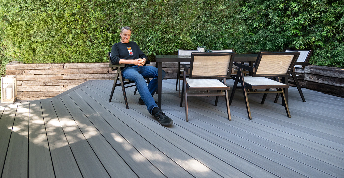 Tony sits with his hands clasped and leans back in his chair with a smile on his new deck.