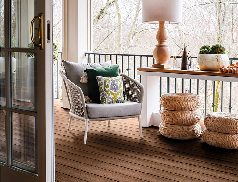 An armchair on the deck next to an entryway table and ceramics makes the space feel very like an easy indoor-outdoor transition.